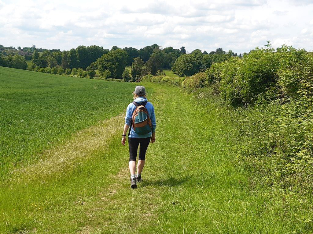 woman walking in the sunshine along grassy path