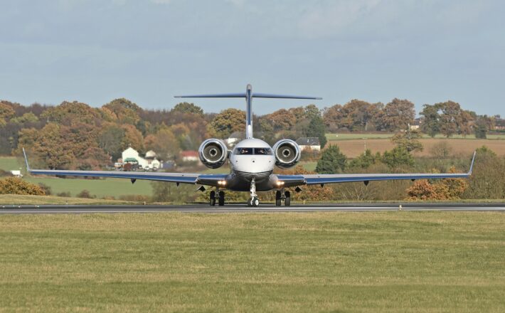 private jet prior to take off at luton airport, green countryside and woodland in the background