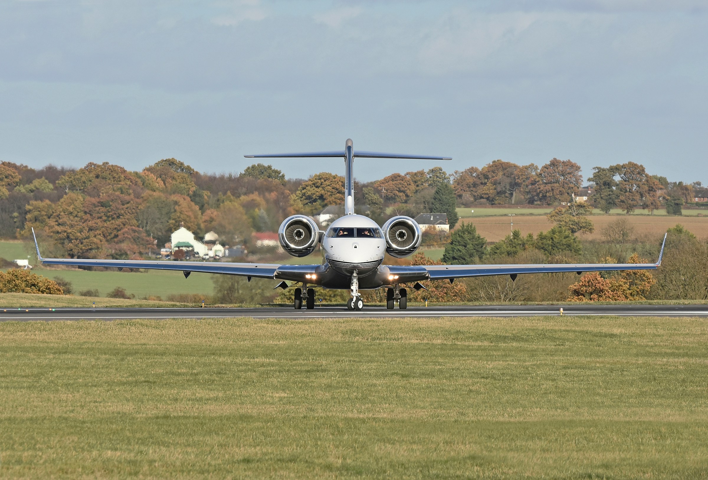 private jet prior to take off at luton airport, green countryside and woodland in the background